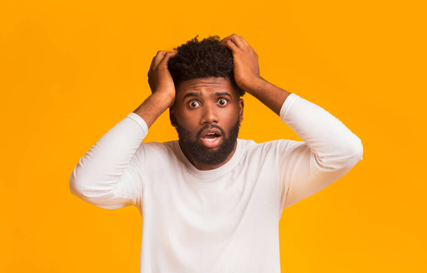 Shocked black guy with open mouth touching his head - Photo, Image