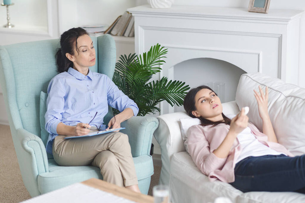 Masentunut nainen jakaa ajatuksiaan terapeutin kanssa yksityisellä istunnolla
 - Valokuva, kuva