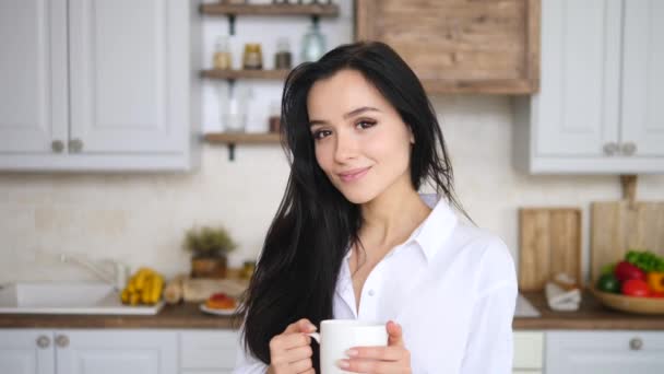 Young Cute Girl With Long Brunette Hair Holding Cup Of Tea And Smiling. - Séquence, vidéo
