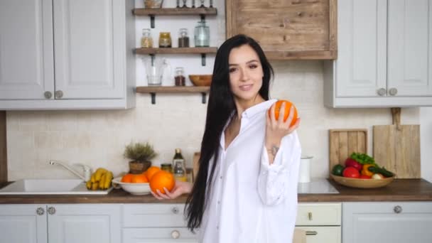 Happy Young Female Playing With Orange In Kitchen - Video