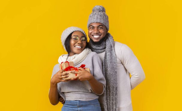 Chica africana feliz sosteniendo regalos de Navidad, sorpresa del hombre amado
 - Foto, imagen