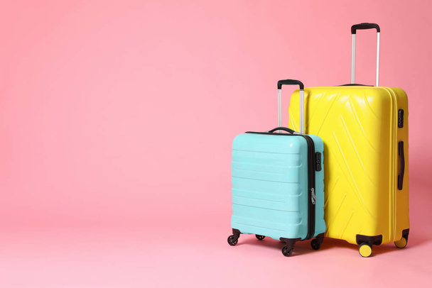 Stylish yellow and turquoise suitcases on pink background. Space - Фото, зображення