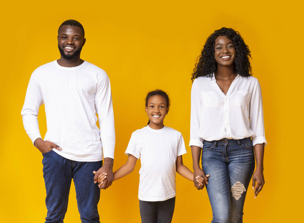 Feliz familia negra tomados de la mano y sonriendo a la cámara
 - Foto, Imagen