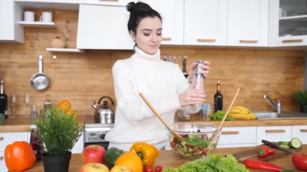 Young Woman Adding Salt To The Bowl While Cooking Salad In Kitchen. - Materiał filmowy, wideo