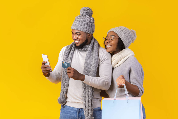 Νεαρό μαύρο ζευγάρι ψώνια σε απευθείας σύνδεση με τηλέφωνο και πιστωτική κάρτα - Φωτογραφία, εικόνα