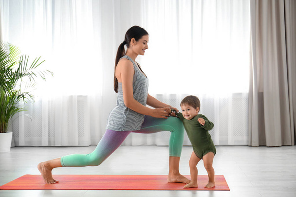 Young woman doing exercise with her son indoors. Home fitness - Foto, Imagen