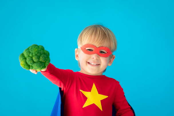 Superhero child holding broccoli - Fotó, kép