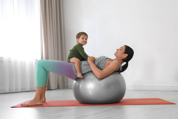 Young woman doing exercise with her son indoors. Home fitness - Foto, Bild