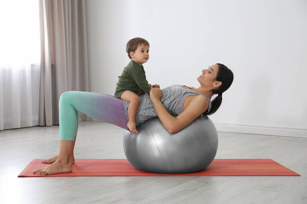 Young woman doing exercise with her son indoors. Home fitness - Fotó, kép