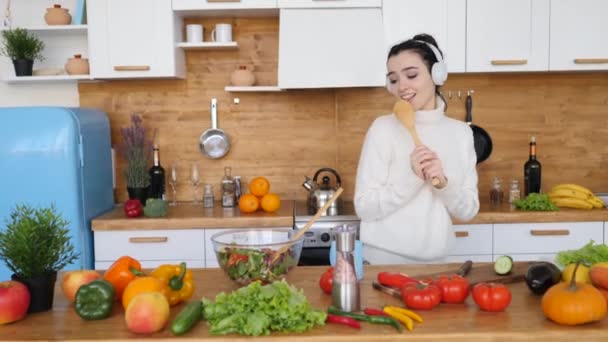 Young Woman Singing In The Kitchen Wearing Headphones - Filmmaterial, Video