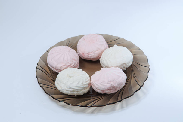 Malvaviscos rosados y blancos sobre un plato marrón sobre un fondo blanco
 - Foto, imagen