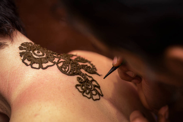 Zeichnungsprozess von Henna-mehendi-Ornament auf dem Rücken der Frau - Foto, Bild