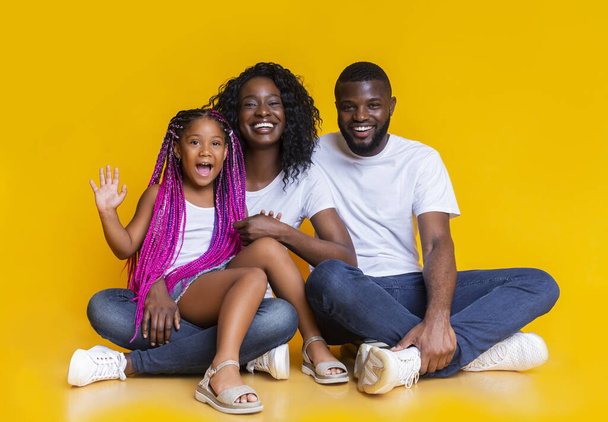 三つの抱擁の幸せな黒の家族とカメラにポーズ - 写真・画像