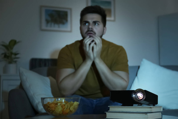 Young man watching movie at home, focus on video projector - Φωτογραφία, εικόνα