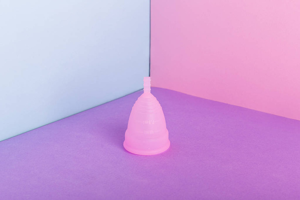 Pink reusable menstrual cup on color background. Woman critical days, gynecological menstruation cycle. Menstruation sanitary woman hygiene. Eco friendly Zero waste concept - Zdjęcie, obraz