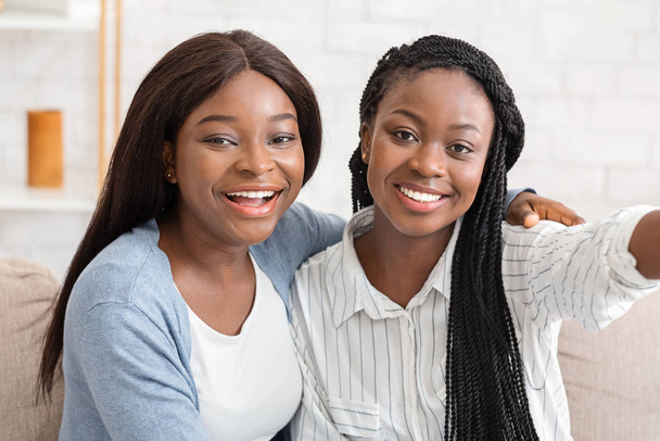 Two cheerful black girlfriends taking selfie, spending time together at home - Fotoğraf, Görsel