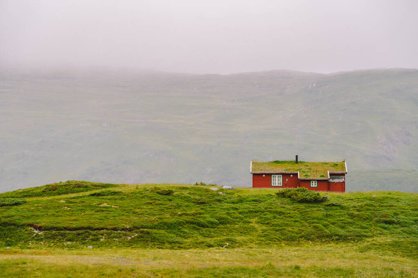 Hütte hölzerne Berghütten in Passnorwegen. norwegische Landschaft mit typisch skandinavischen Grasdachhäusern. Bergdorf mit kleinen Häusern und Holzhütten mit Gras auf dem Dach im Tal - Foto, Bild