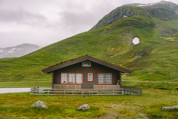 καλύβα ξύλινα καλύβες βουνό στο ορεινό πέρασμα της Νορβηγίας. Νορβηγικό τοπίο με τυπικό σκανδιναβικό χόρτο ταράτσες. Ορεινό χωριό με μικρά σπίτια και ξύλινες καμπίνες με γρασίδι στην οροφή στην κοιλάδα - Φωτογραφία, εικόνα