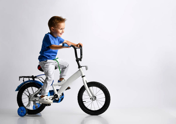 young boy happily riding on a bicycle on isolated background - Photo, image