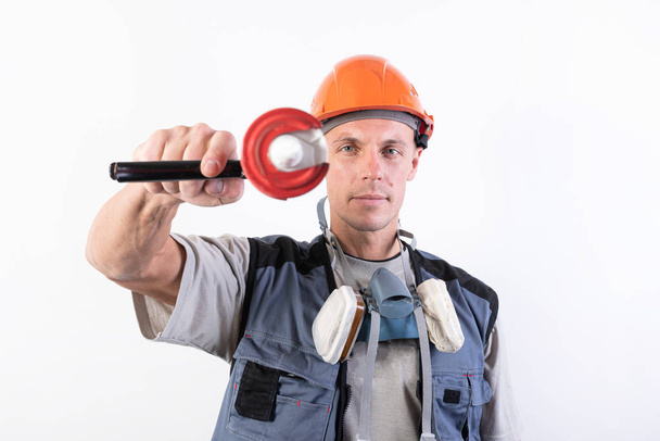 Un constructor en un casco, con silicona en una pistola de montaje, apunta al marco
. - Foto, Imagen