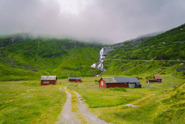 Chata dřevěné horské chaty v horském průsmyku Norsko. Norská krajina s typickými skandinávskými střešními domy. Horská vesnice s malými domky a dřevěnými chatkami s trávou na střeše v údolí - Fotografie, Obrázek