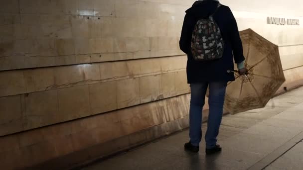 Nierozpoznawalna kobieta stoi na peronie metra z otwartym parasolem i obrotami - Materiał filmowy, wideo