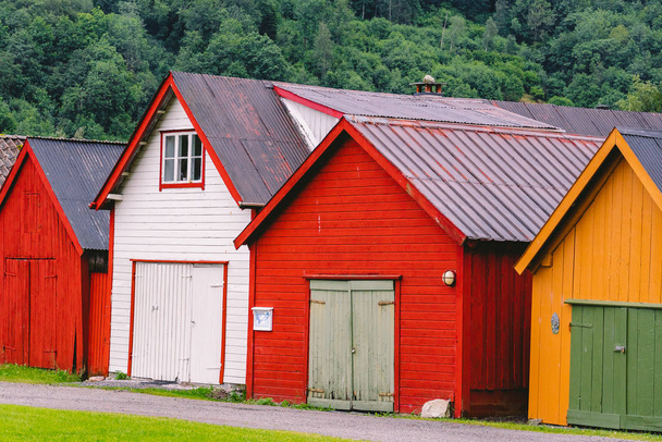 Widok wsi kolorowe drewniane budynki. Domki na łodzie w Norwegii. Skandynawskie tradycyjne łodzie. wielokolorowy garaż drewniane domy w nadmorskiej norweskiej wiosce rybackiej - Zdjęcie, obraz