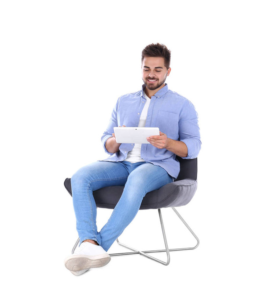 Young man with tablet sitting in armchair isolated on white - Foto, Imagen