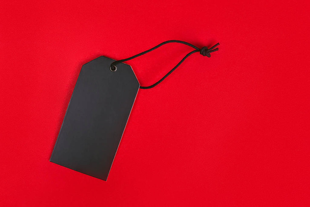 Blank black tag on red background with copy space. Price tag, gift tag, sale tag, address label, etc. - Fotografie, Obrázek