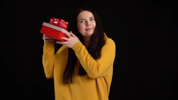 Young woman with a gift box on black background. gift box with white ribbon for Happy New Year, Merry Christmas, Valentines Day, birthday. - Video