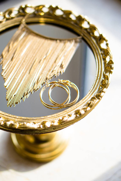 Gouden oorbellen en ketting op spiegel lade - Foto, afbeelding