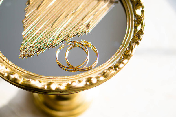Boucles d'oreilles et collier dorés sur plateau miroir
 - Photo, image