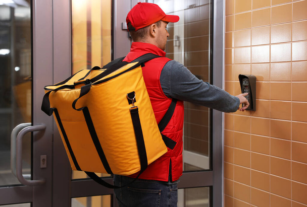 Male courier with thermo bag pushing intercom button. Food delivery service - Fotó, kép