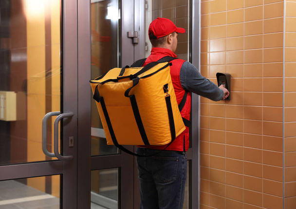 Male courier with thermo bag pushing intercom button. Food delivery service - Foto, Imagem