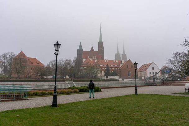 Hombre mirando a Cathedral Island Ostrow Tumski y Odra River en un día nublado de otoño en Wroclaw
 - Foto, imagen