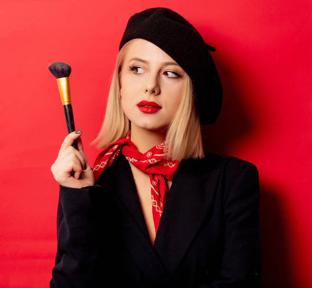 bella donna francese in berretto con pennello trucco sul retro rosso
 - Foto, immagini