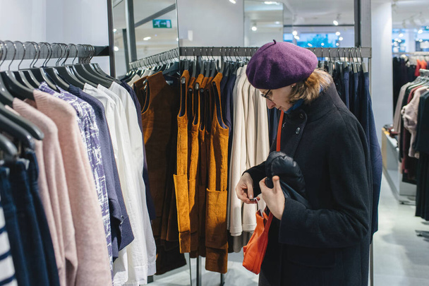 Покупка сумочки из оранжевой кожи в модном магазине одежды
 - Фото, изображение