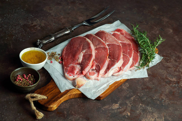 rohe frische Lammkoteletts Steak auf dem Schneidebrett, auf dem Betongrund mit Rosmarin und Salz - Foto, Bild