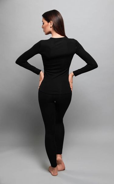 Woman wearing thermal underwear on grey background, back view - Zdjęcie, obraz