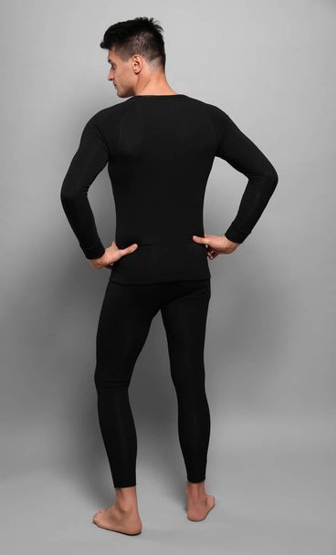 Man wearing thermal underwear on grey background, back view - Valokuva, kuva