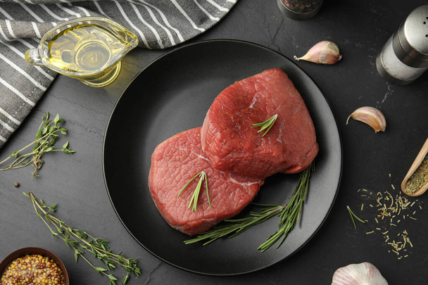 Flat lay composition with fresh beef cut on black table - Photo, image