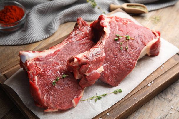 Fresh raw beef cut with thyme and salt on wooden table, closeup - Φωτογραφία, εικόνα
