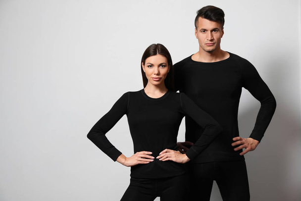 Couple wearing thermal underwear on light grey background. Space for text - Φωτογραφία, εικόνα