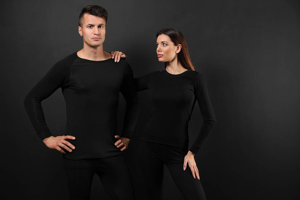 Couple wearing thermal underwear on black background - Zdjęcie, obraz
