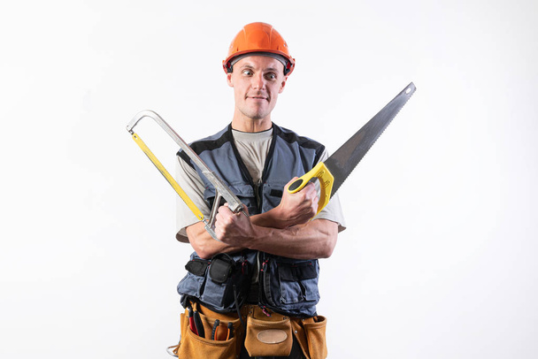 Ein Bauarbeiter mit Hacksäge im Helm spottet. auf hellem Hintergrund. - Foto, Bild
