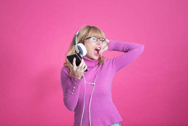 mulher adulta dançando feliz com fones de ouvido e telefone celular
 - Foto, Imagem