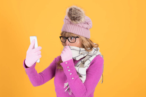woman in winter with mobile phone on color background - Фото, изображение