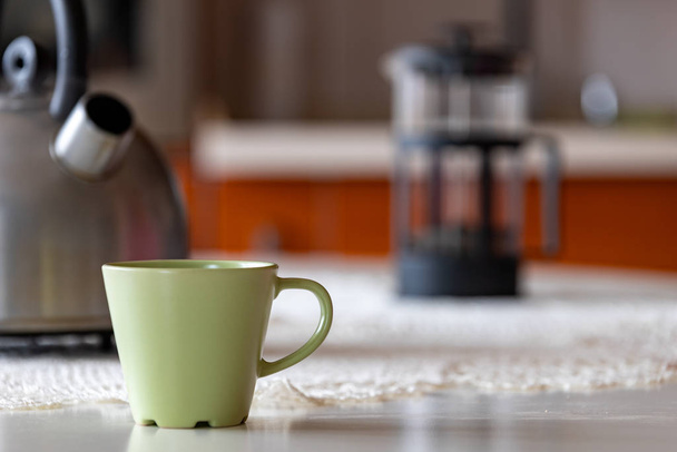 Coffee cup and metal kettle on the kitchen table.  - Photo, image
