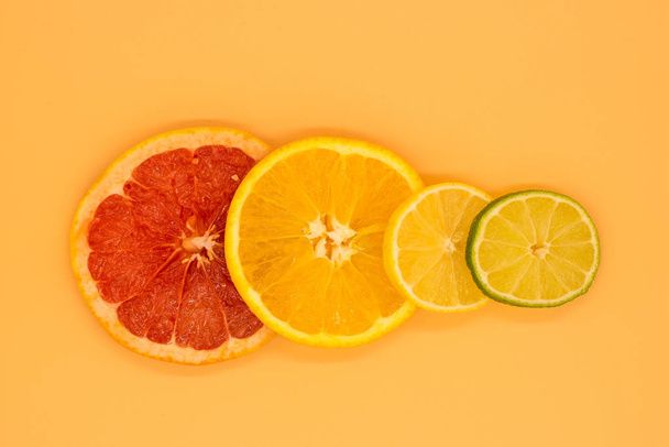 various citrus slices of orange lime lemon and grapefruit arranged on colorful background abstract wallpaper with copy space - Photo, Image