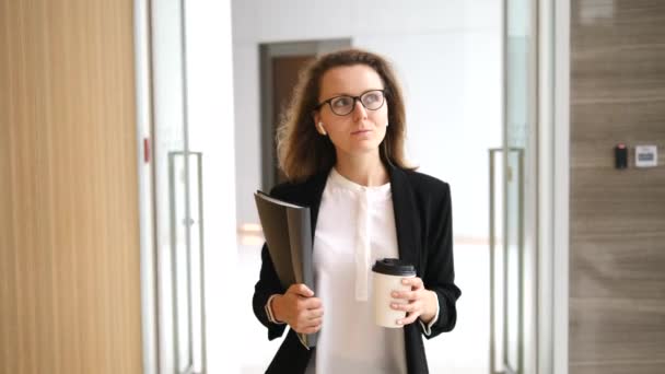 Confident Businesswoman In Wireless Earphones Going To Work With Coffee - Imágenes, Vídeo